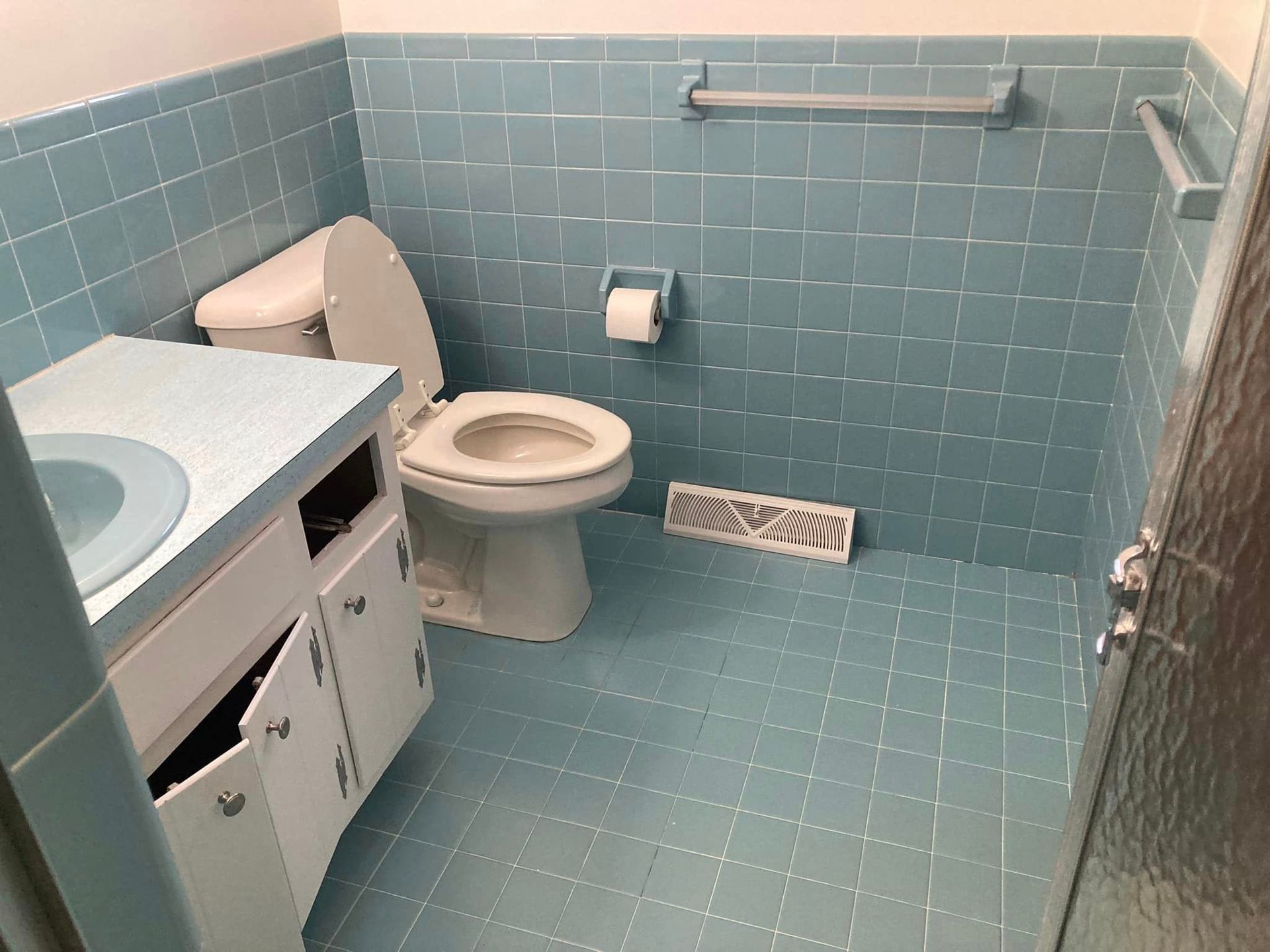 A bathroom with blue tiles and a toilet