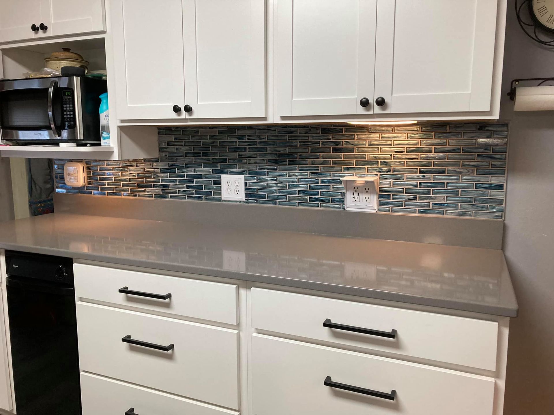 A kitchen with white cabinets and black handles