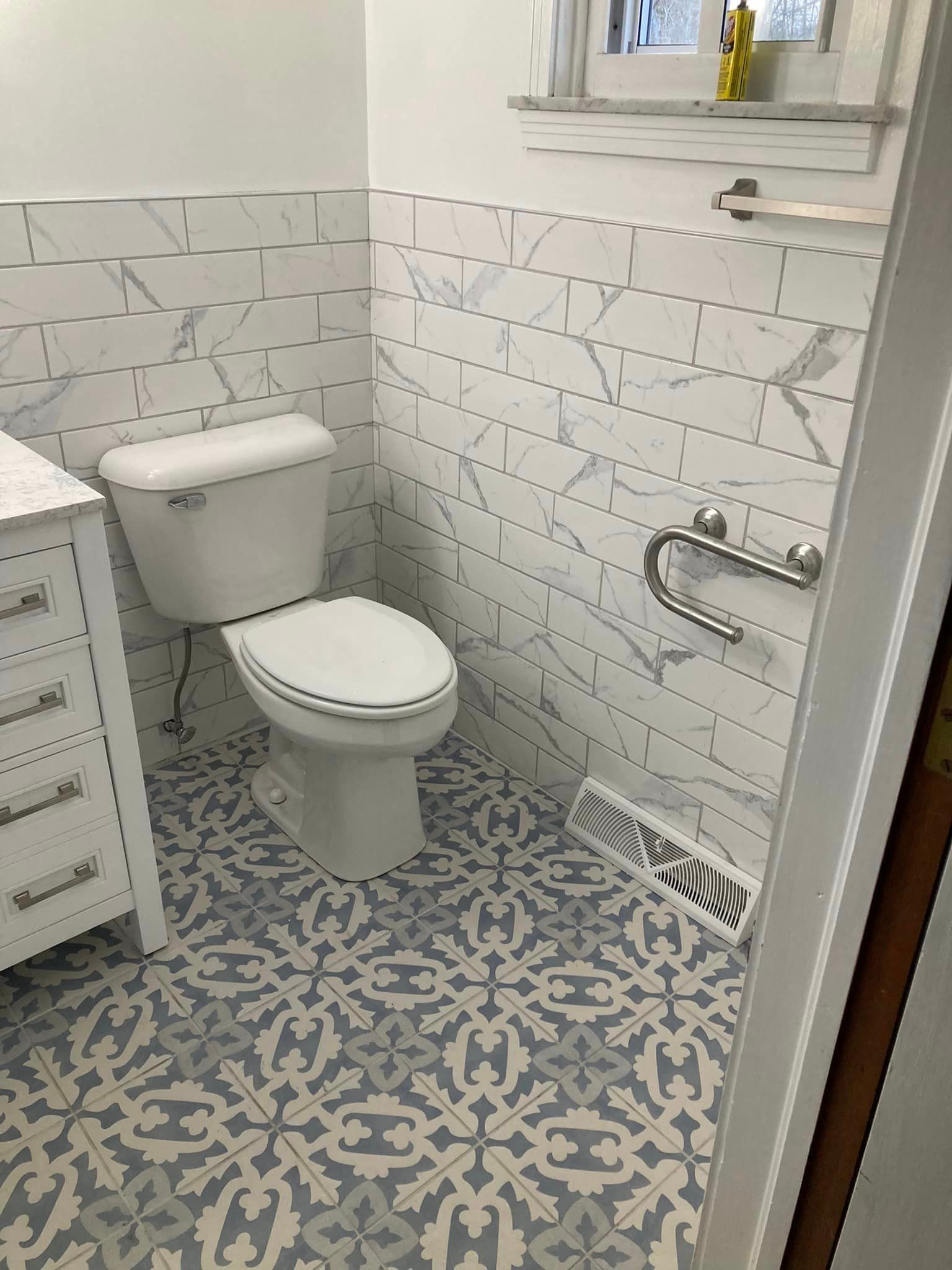 A bathroom with blue and white tiles and a toilet
