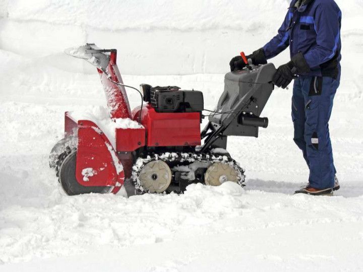 A man is using a snow blower in the snow