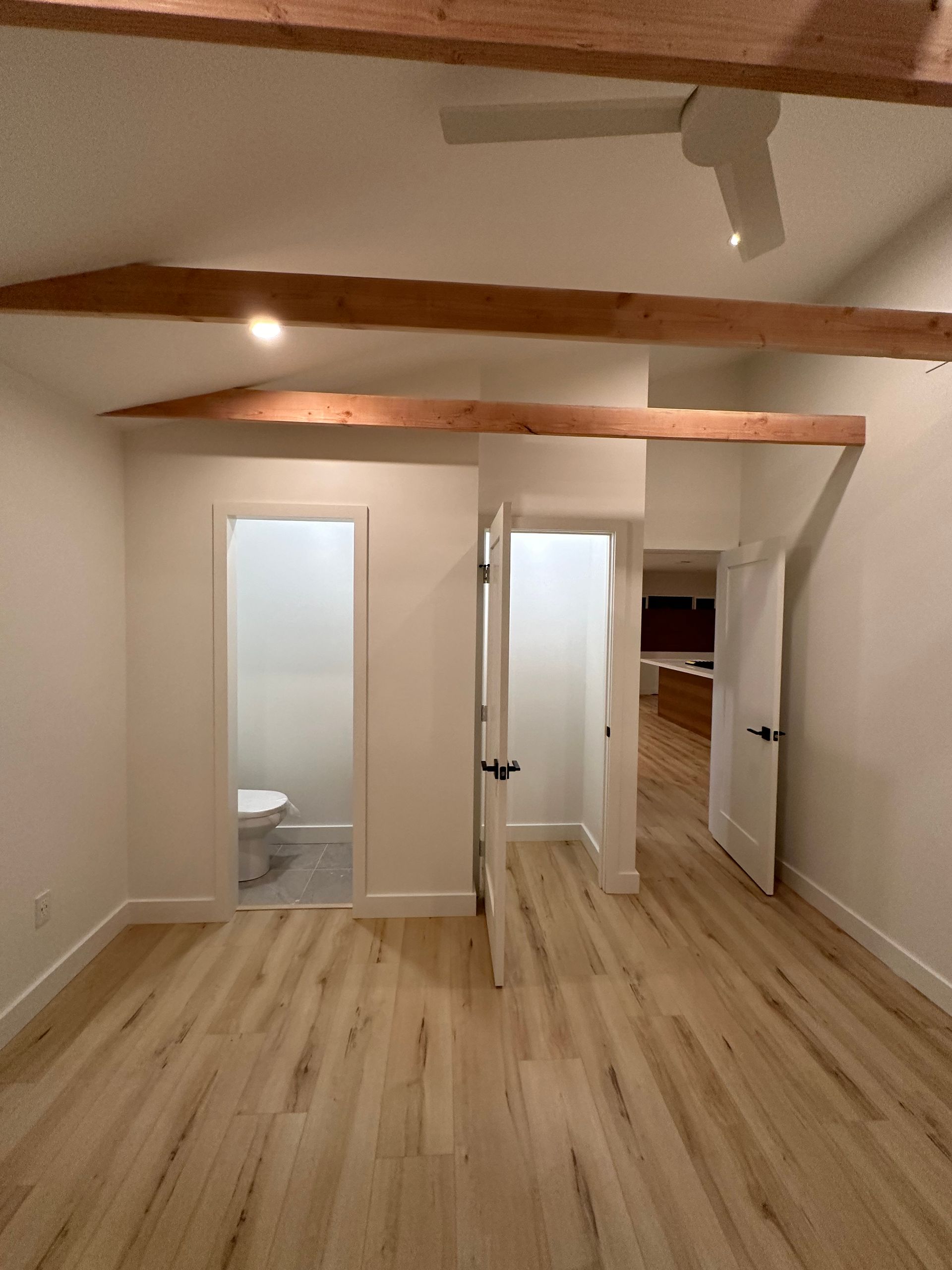 An empty room with wooden floors and a ceiling fan.