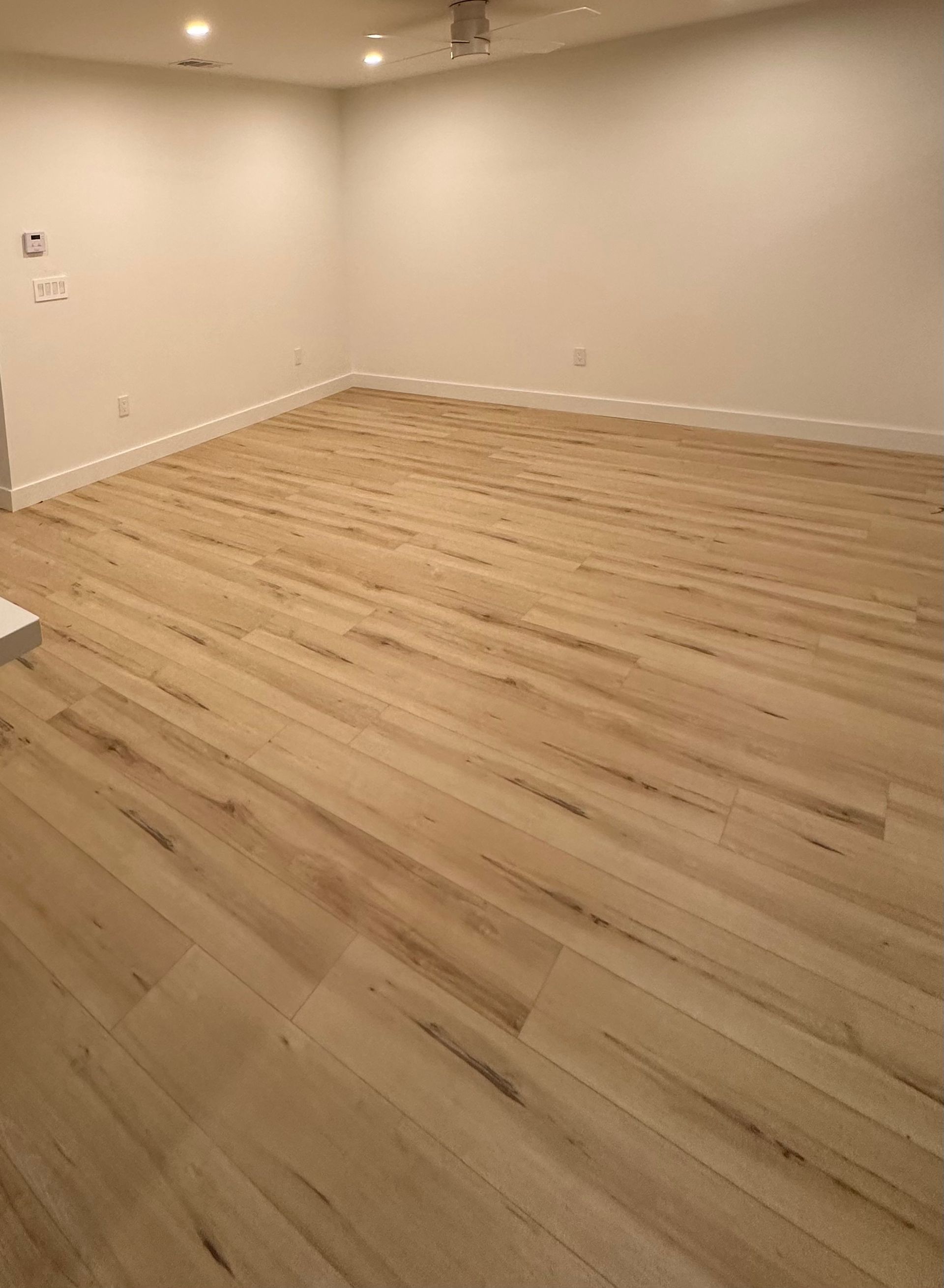 An empty room with wooden floors and white walls.