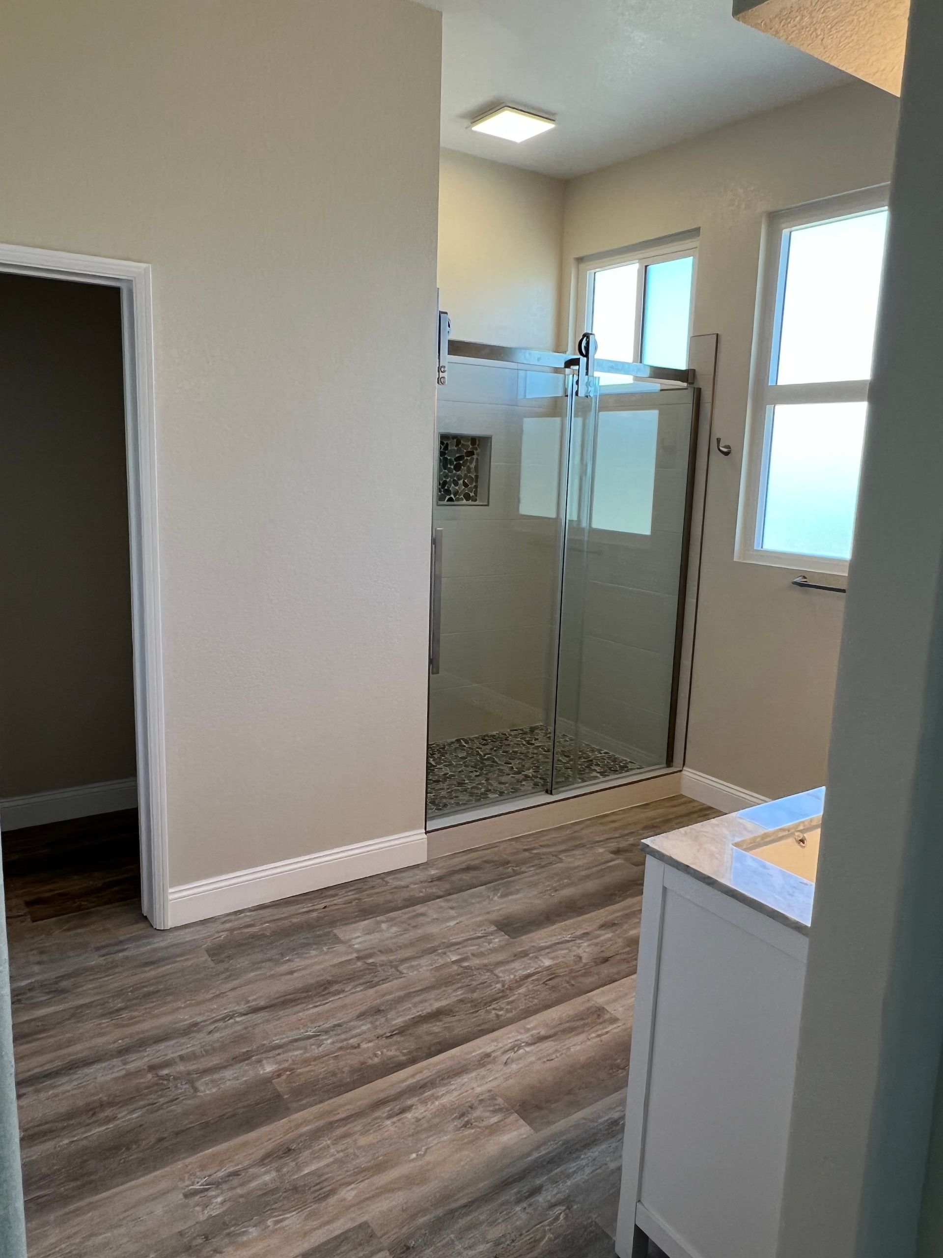 A bathroom with a walk in shower and a sink.