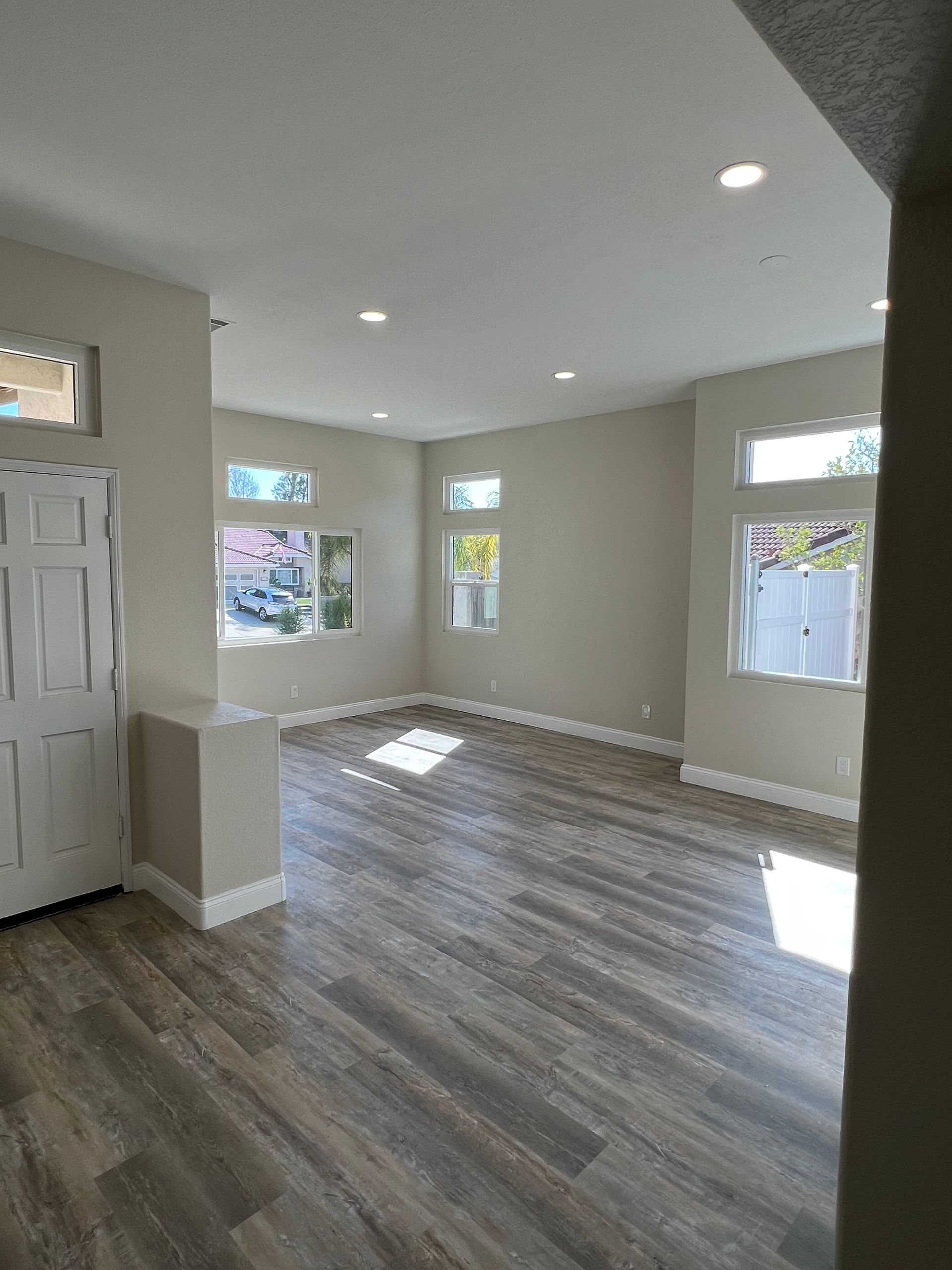 An empty living room with hardwood floors and lots of windows.