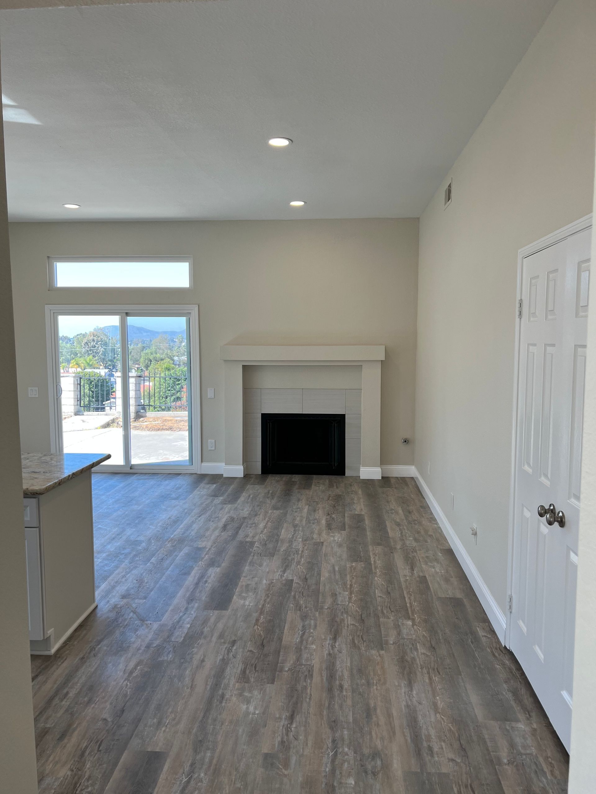 An empty living room with a fireplace and sliding glass doors.