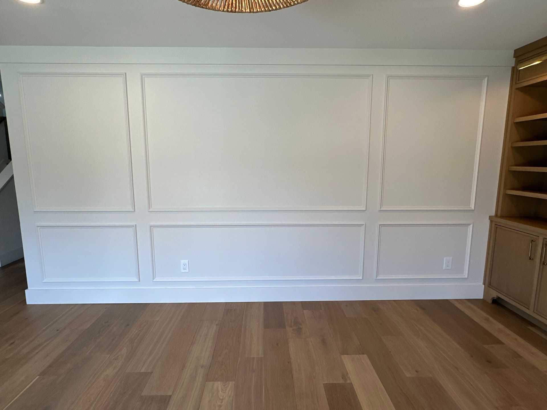 There is a large white wall in the middle of the room with wooden floors.