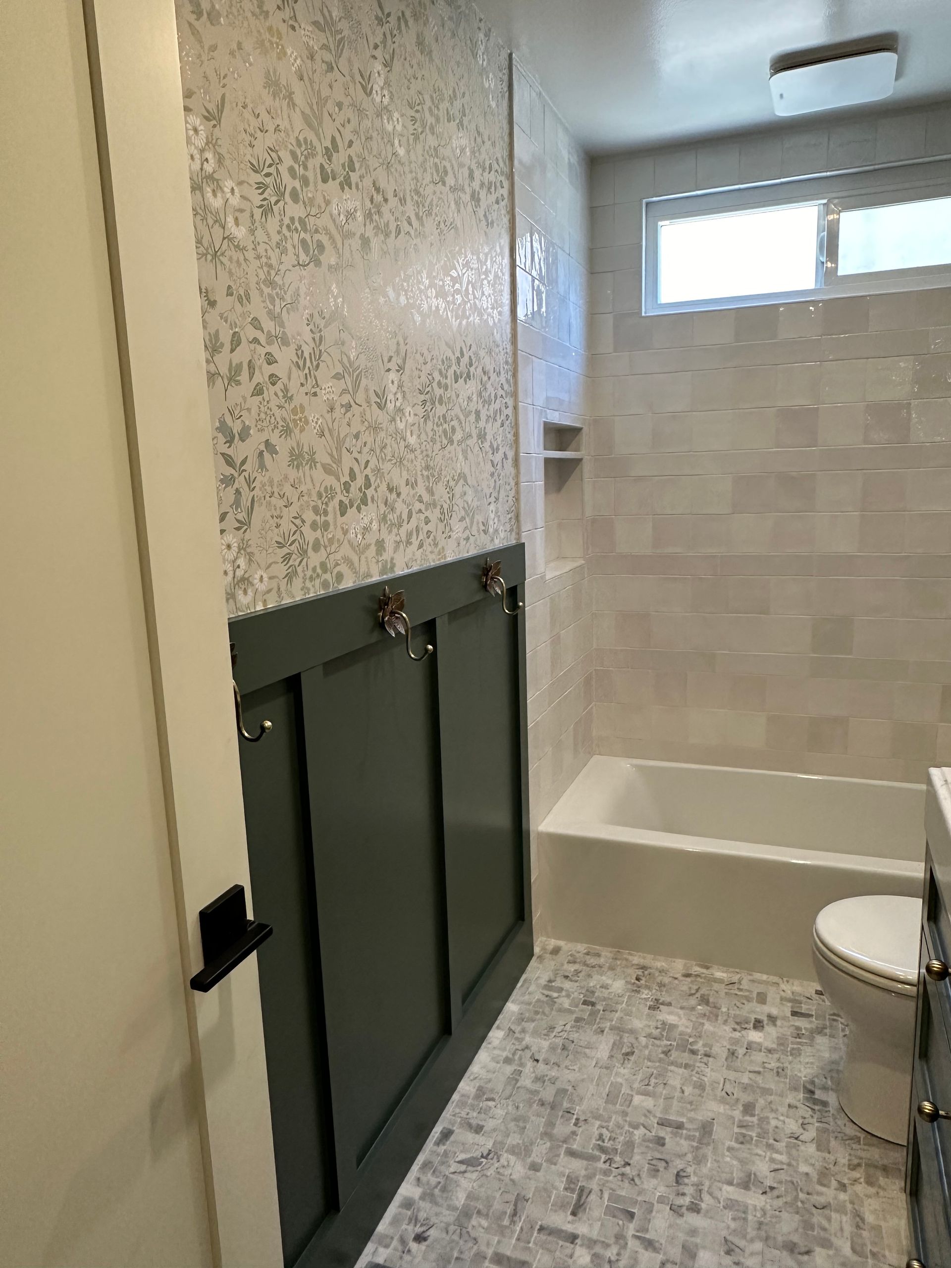 A bathroom with a toilet , tub , shower and window.