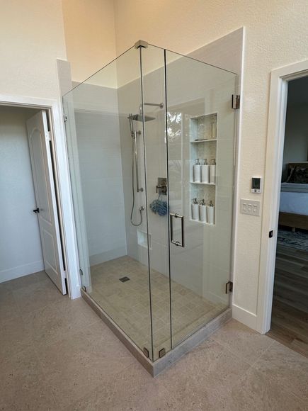 A bathroom with a walk in shower with a glass door.