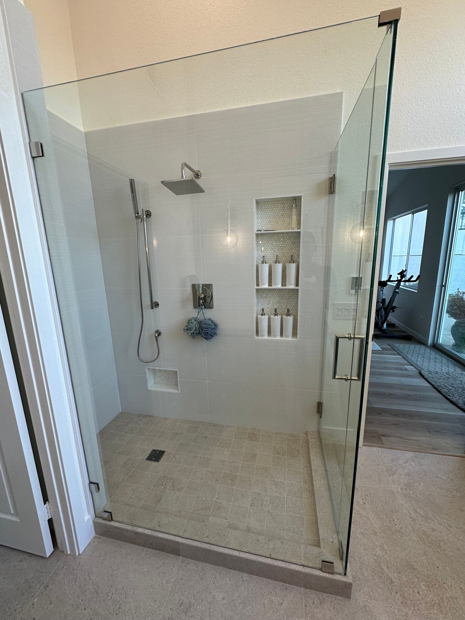 A bathroom with a walk in shower with a glass door.