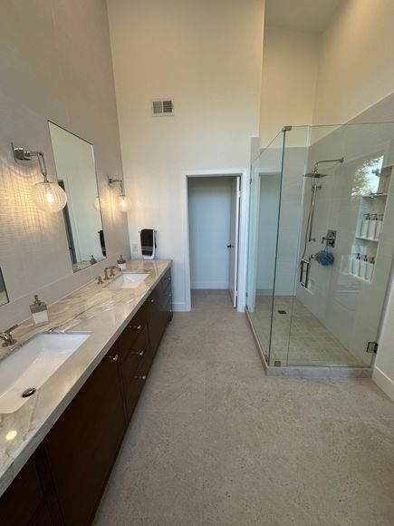 A bathroom with two sinks and a walk in shower.