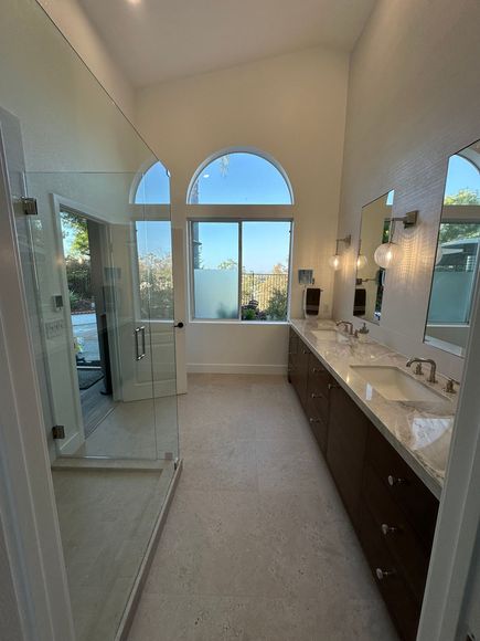 A bathroom with two sinks , a shower and a large window.