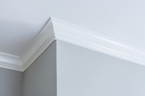 A close up of a white cornice on a white wall.