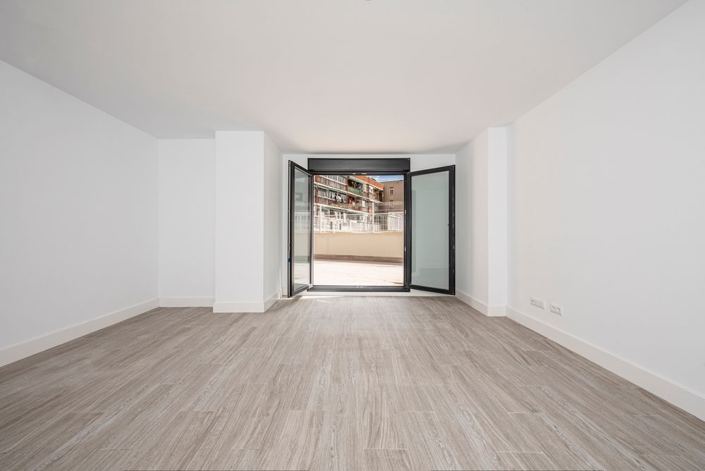 An empty living room with hardwood floors and a balcony.