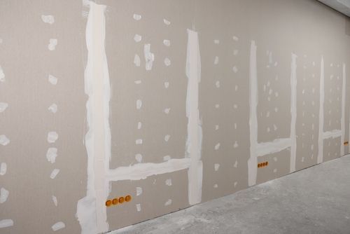 A room with a row of drywall walls and electrical outlets.