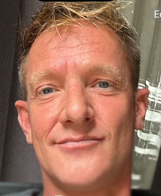 Lori Martorell on beach, looking at sunset over ocean. Warm colors, light reflecting on her face.