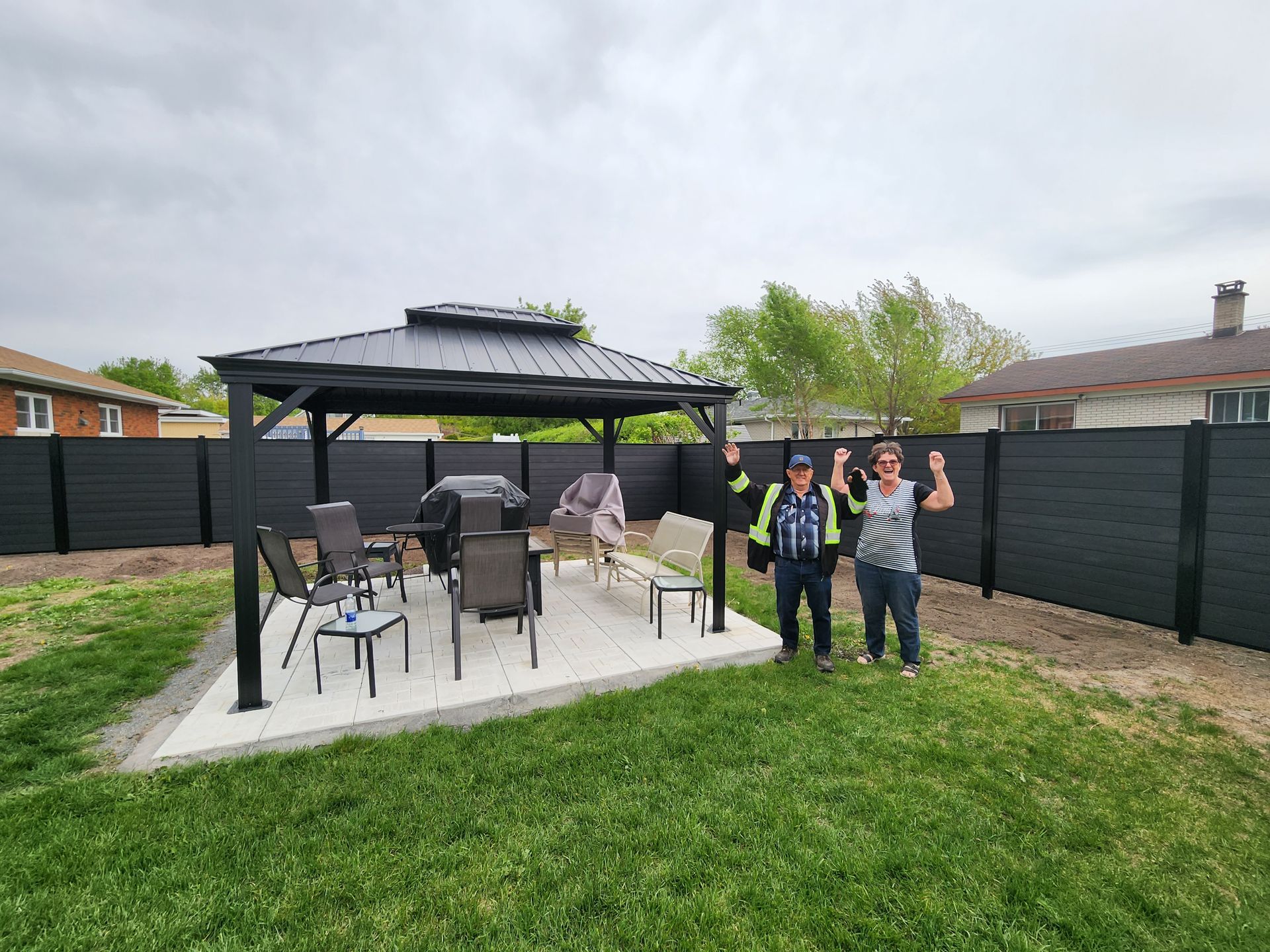 Deux hommes se tiennent devant un belvédère dans une cour arrière.