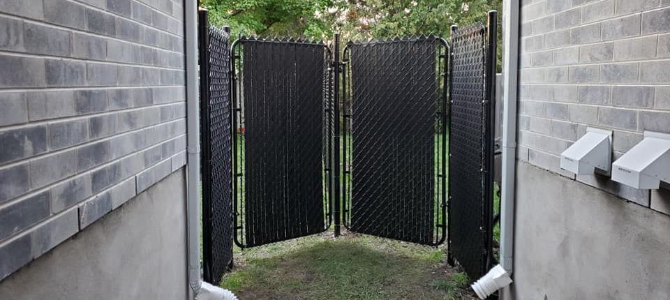 Une clôture à mailles noires se trouve entre deux murs de briques.