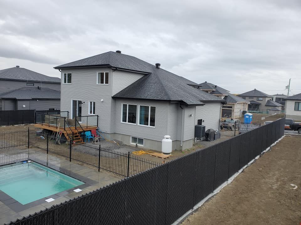 Une maison avec une clôture autour et une piscine dans l'arrière-cour.