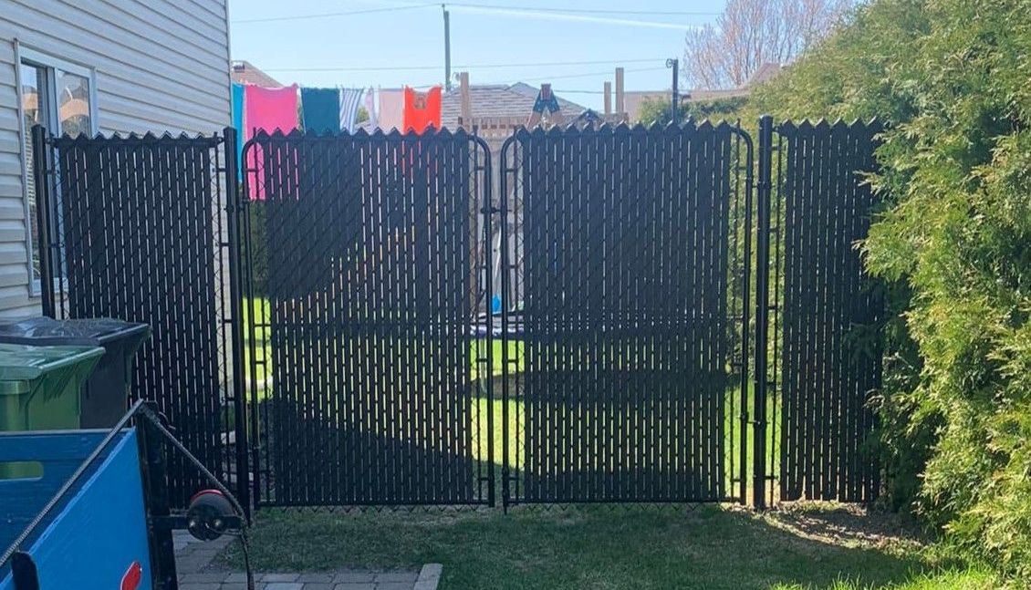 Une clôture noire se trouve dans l'arrière-cour d'une maison.