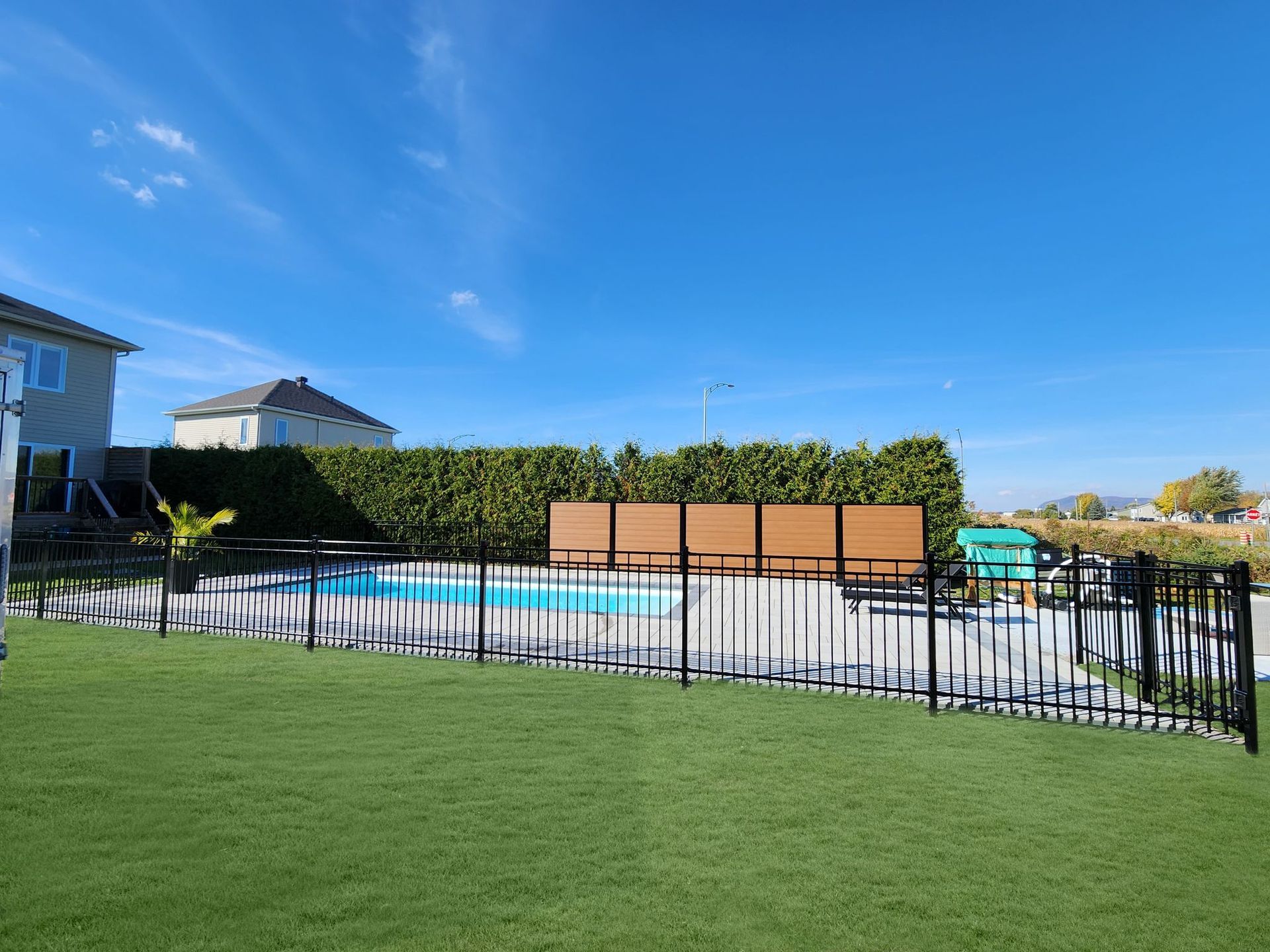 Une clôture entoure une piscine dans une cour arrière.