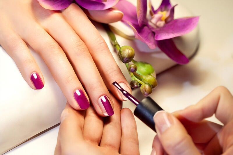 A Woman is Getting her Nails Painted with Purple nail Polish — Bernadette's Beauty Care in Sarina, QLD