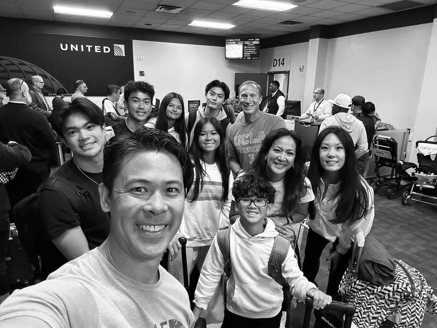 Group of people smiling at camera in United Airlines terminal.