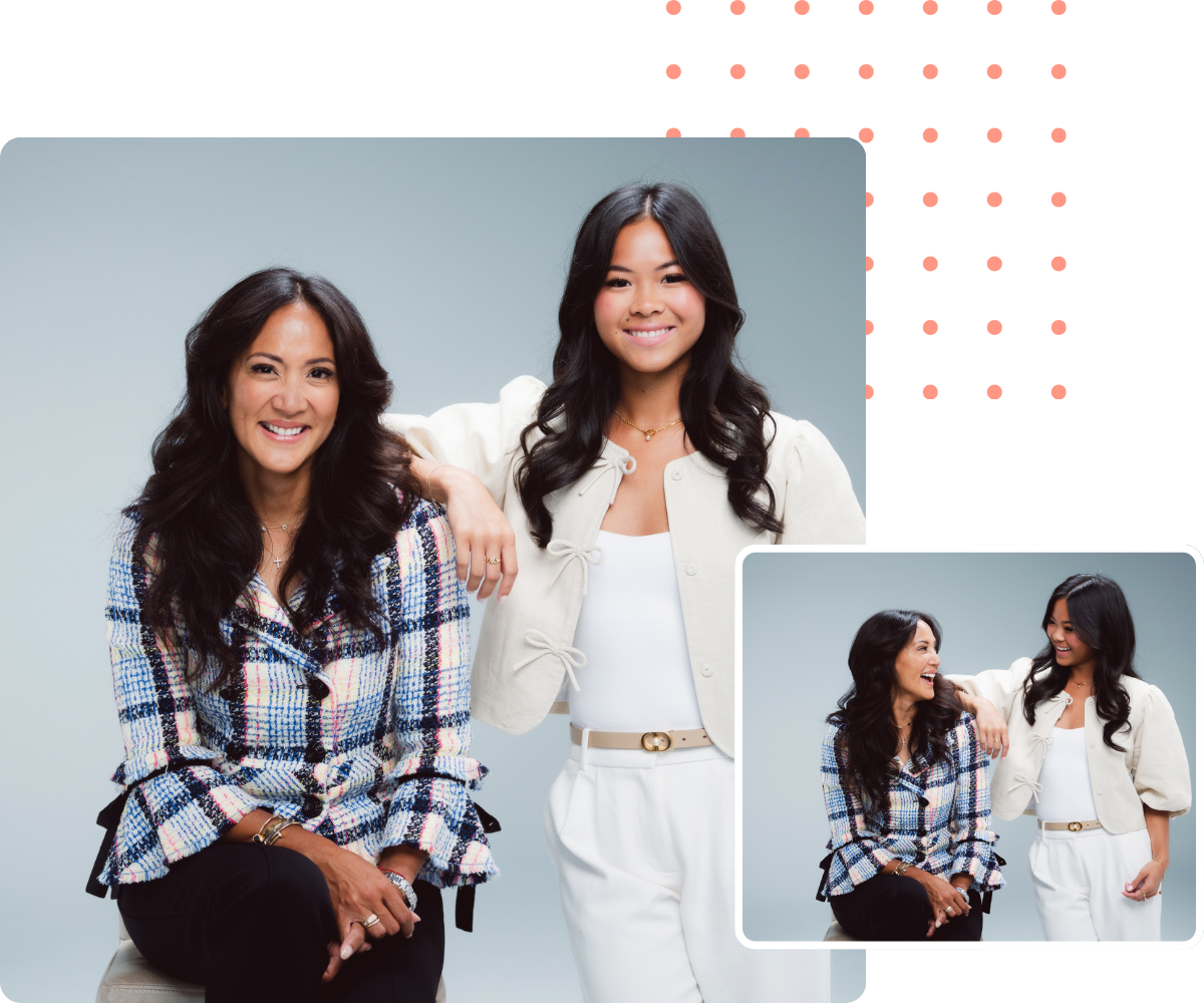 Two women smiling, posing for a portrait. One sits, wearing a blue patterned jacket. The other stands, in a cream jacket.