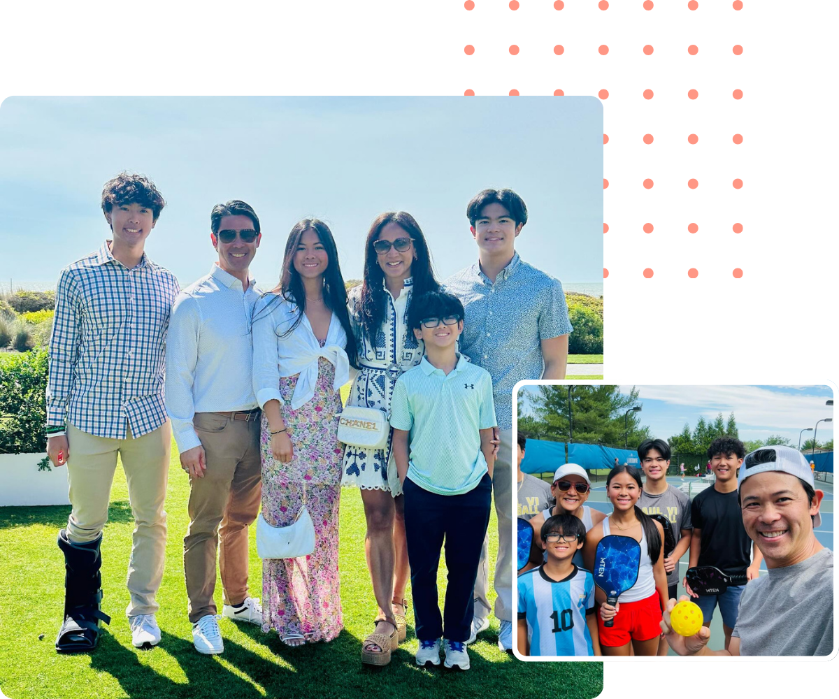 Group of people smiling outdoors, some holding bags. Green grass and blue sky. A cast on one person's leg.