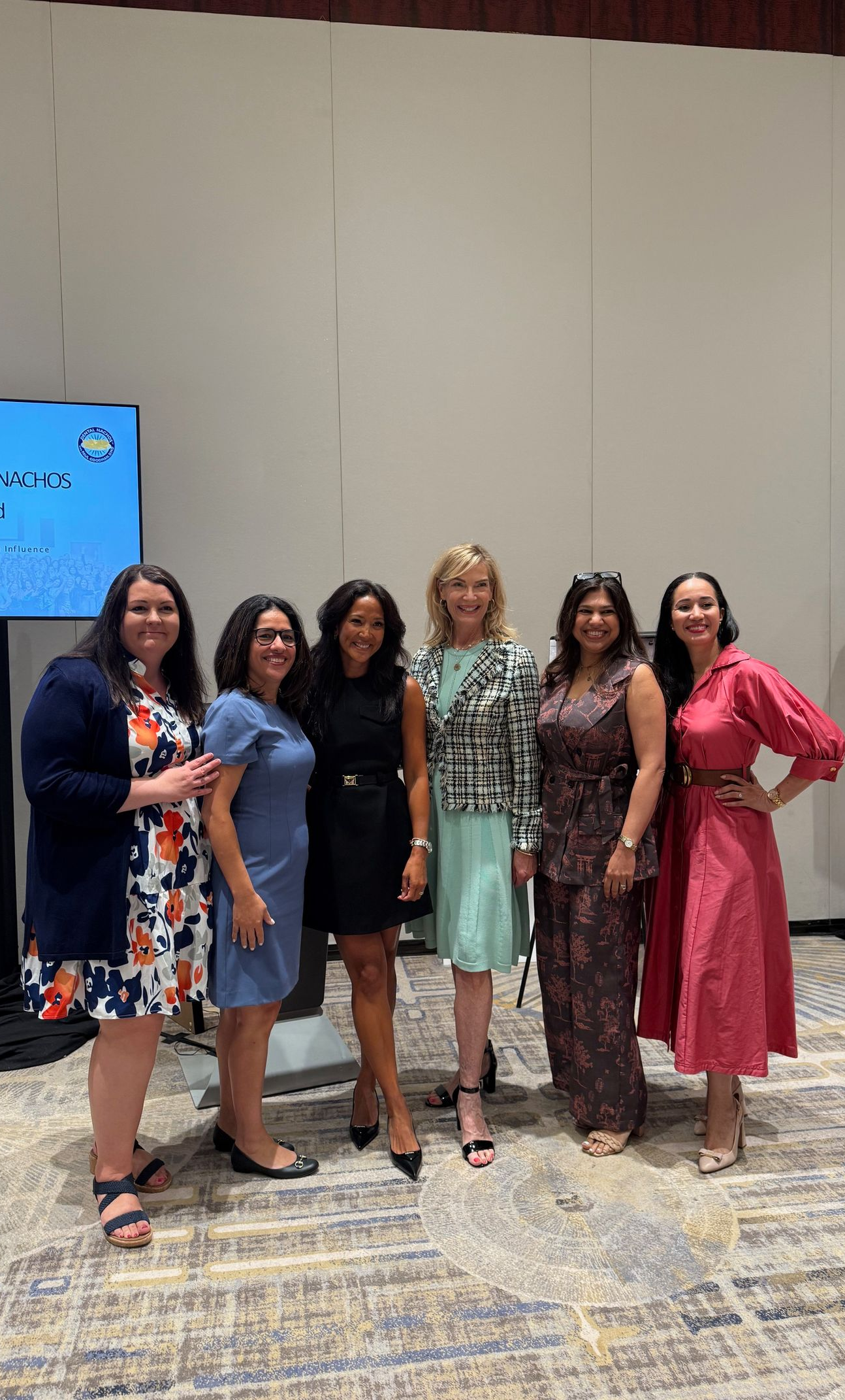Six people in formal wear pose indoors.