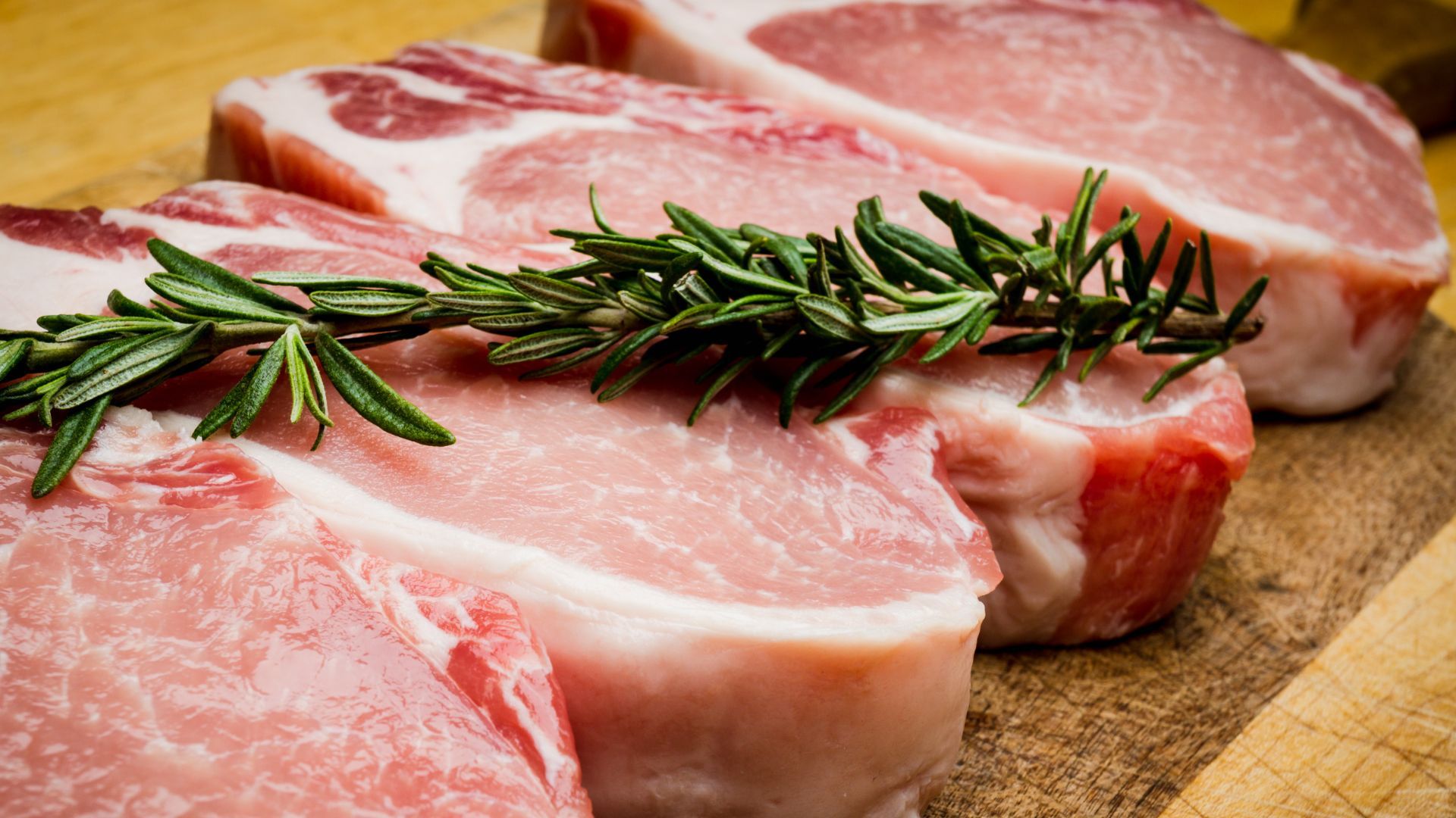 A steak is being sliced on a wooden cutting board.