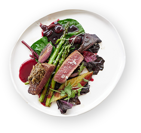 A white plate topped with meat and vegetables on a white background.