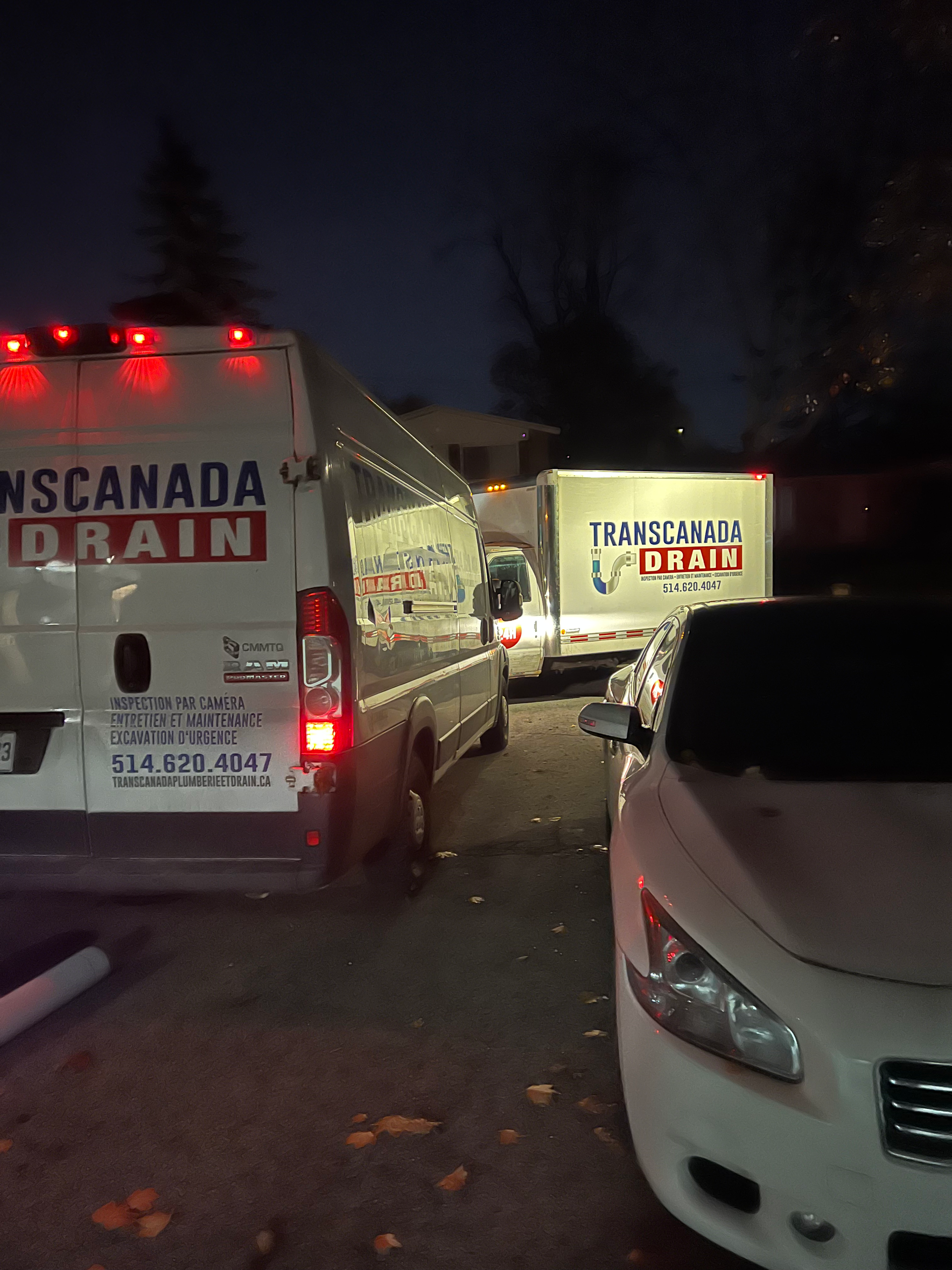 Drainage service vehicles parked at night; white and red logos.