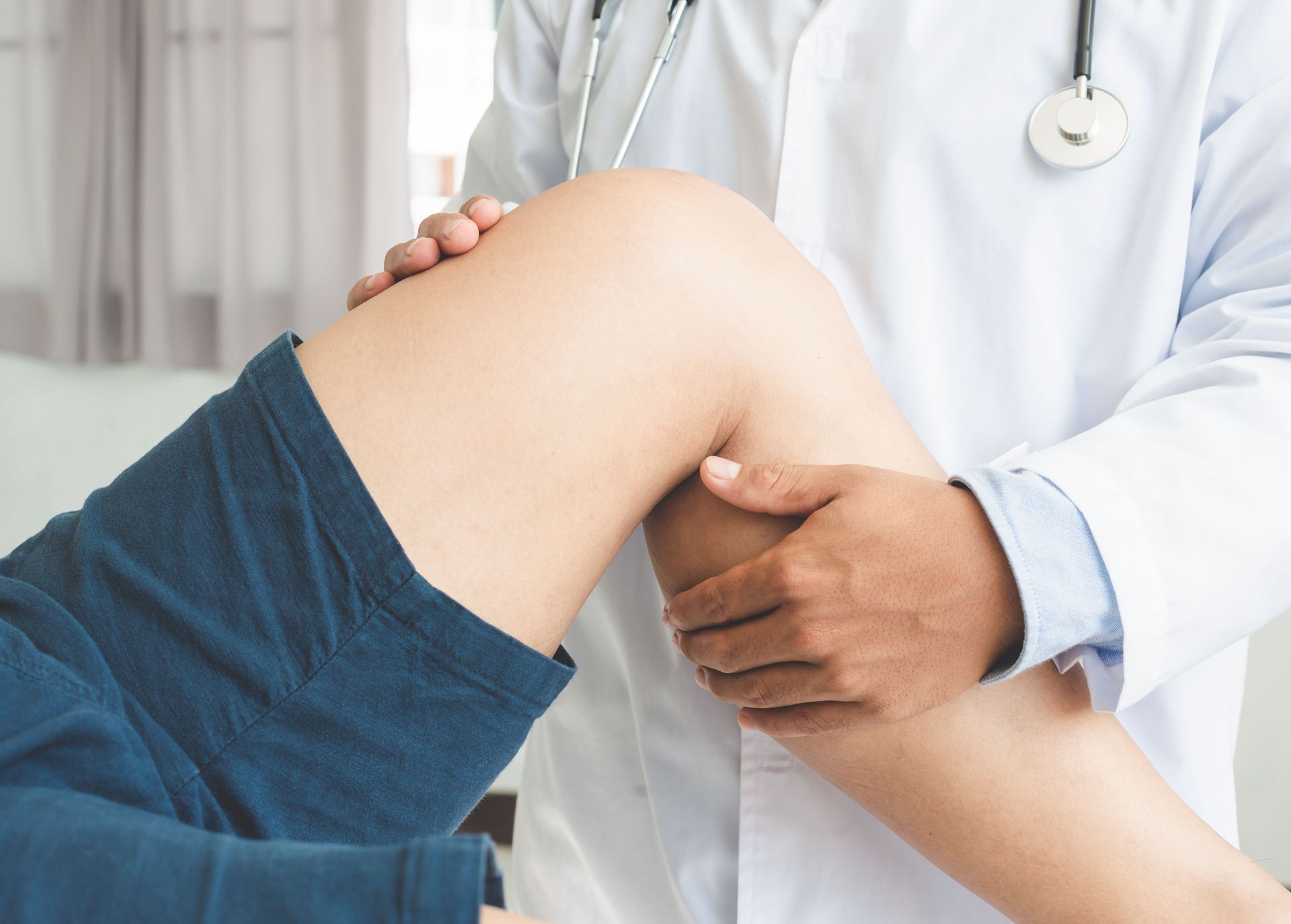 A doctor is examining a patient 's knee in a hospital.