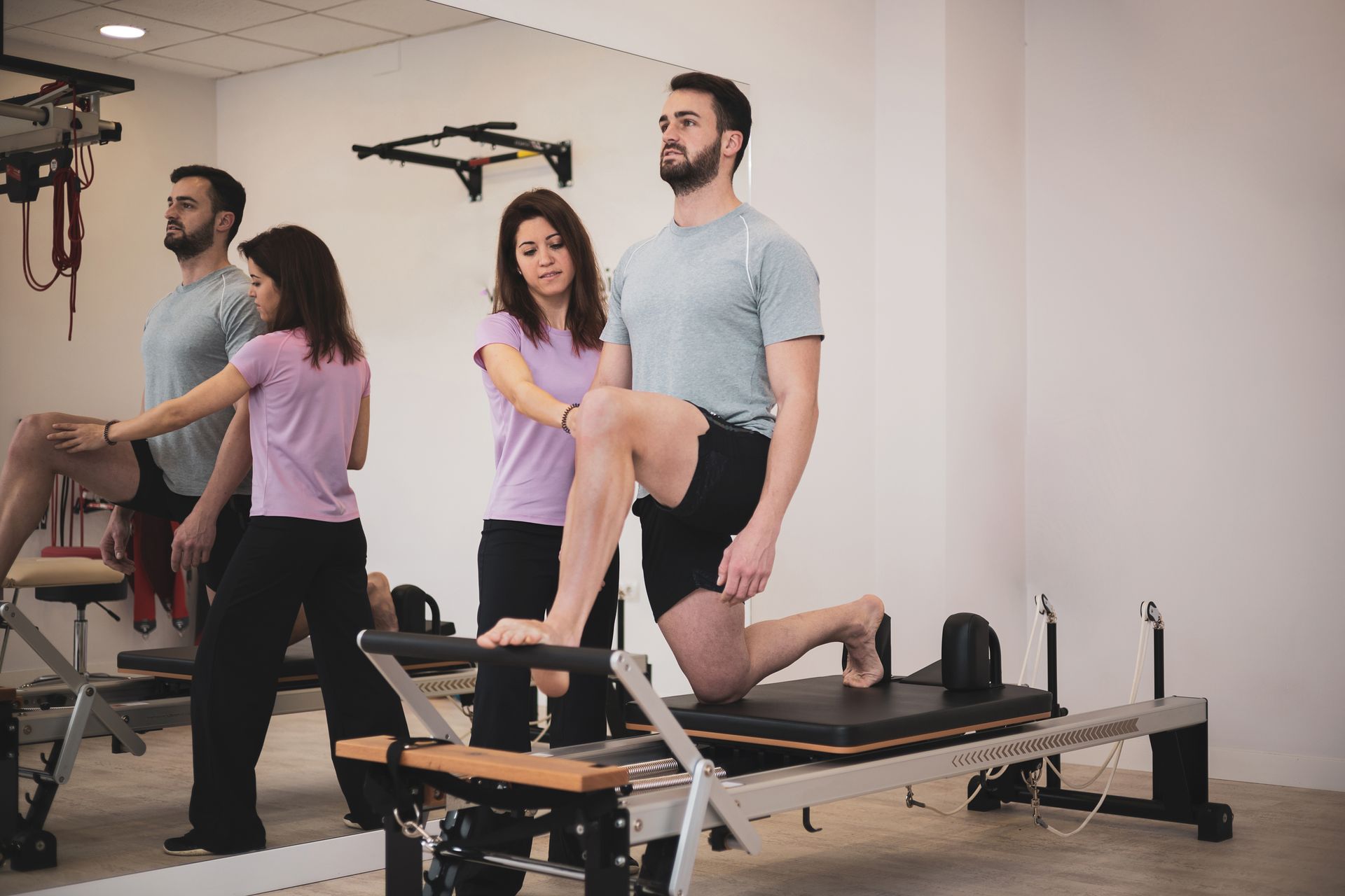 A group of people are doing exercises on a pilates machine in a gym.