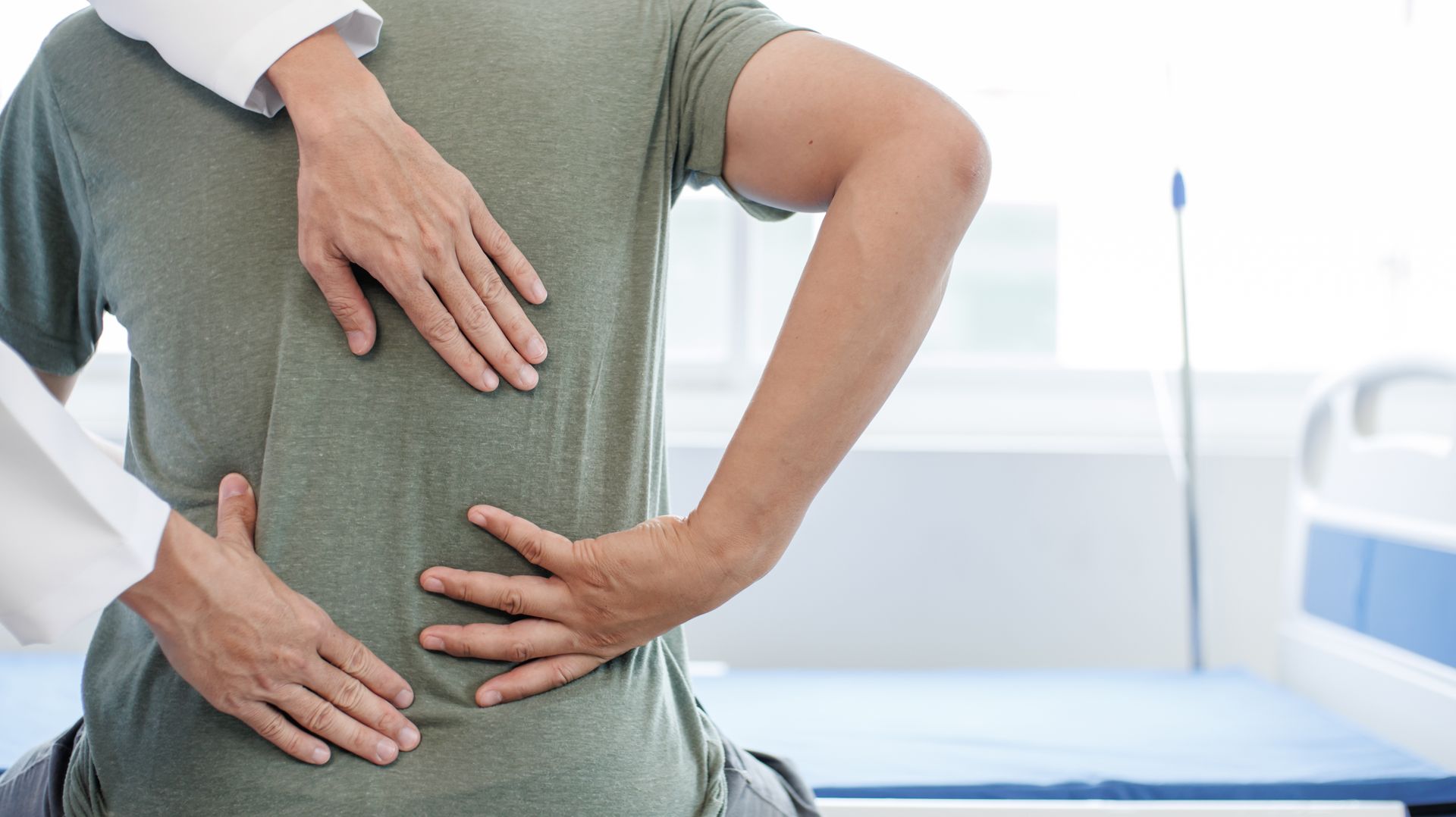 A doctor is examining a patient 's back in a hospital.