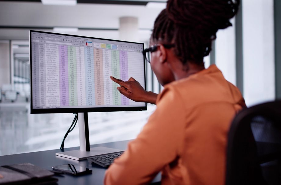 Woman pointing at a spreadsheet on a computer monitor in an medical office setting.