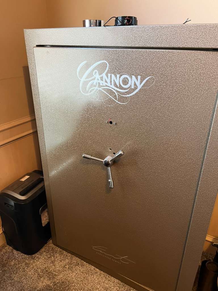 Large tan Cannon safe with a combination dial and handle. A paper shredder is beside it.