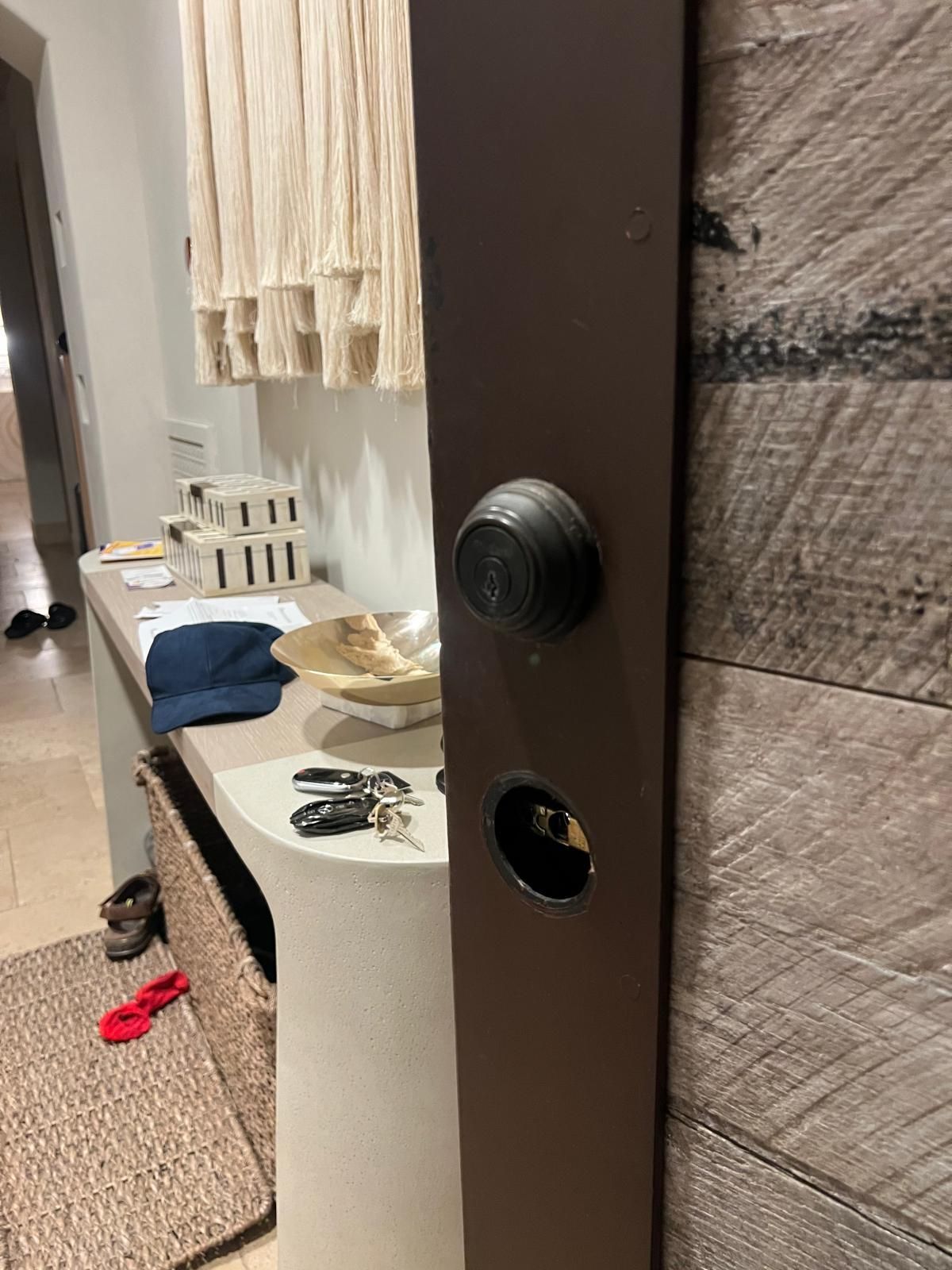 Brown door with lock and keyhole. Keys and items on a nearby table.