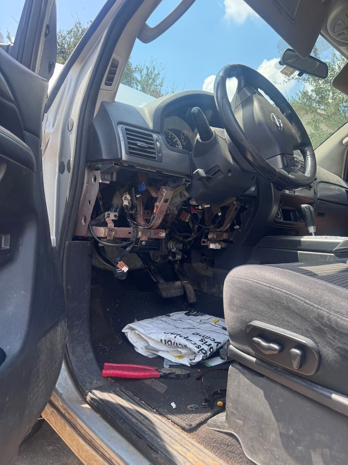 Interior of a car with dashboard components removed, tools visible.