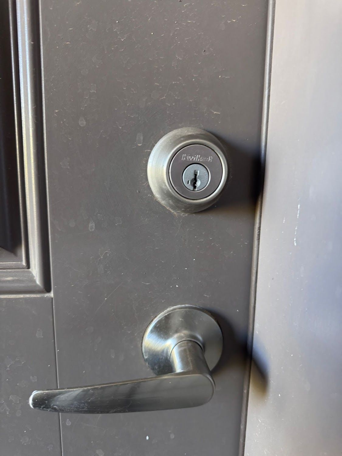 Dark door with silver doorknob and deadbolt lock. The keyhole is visible.