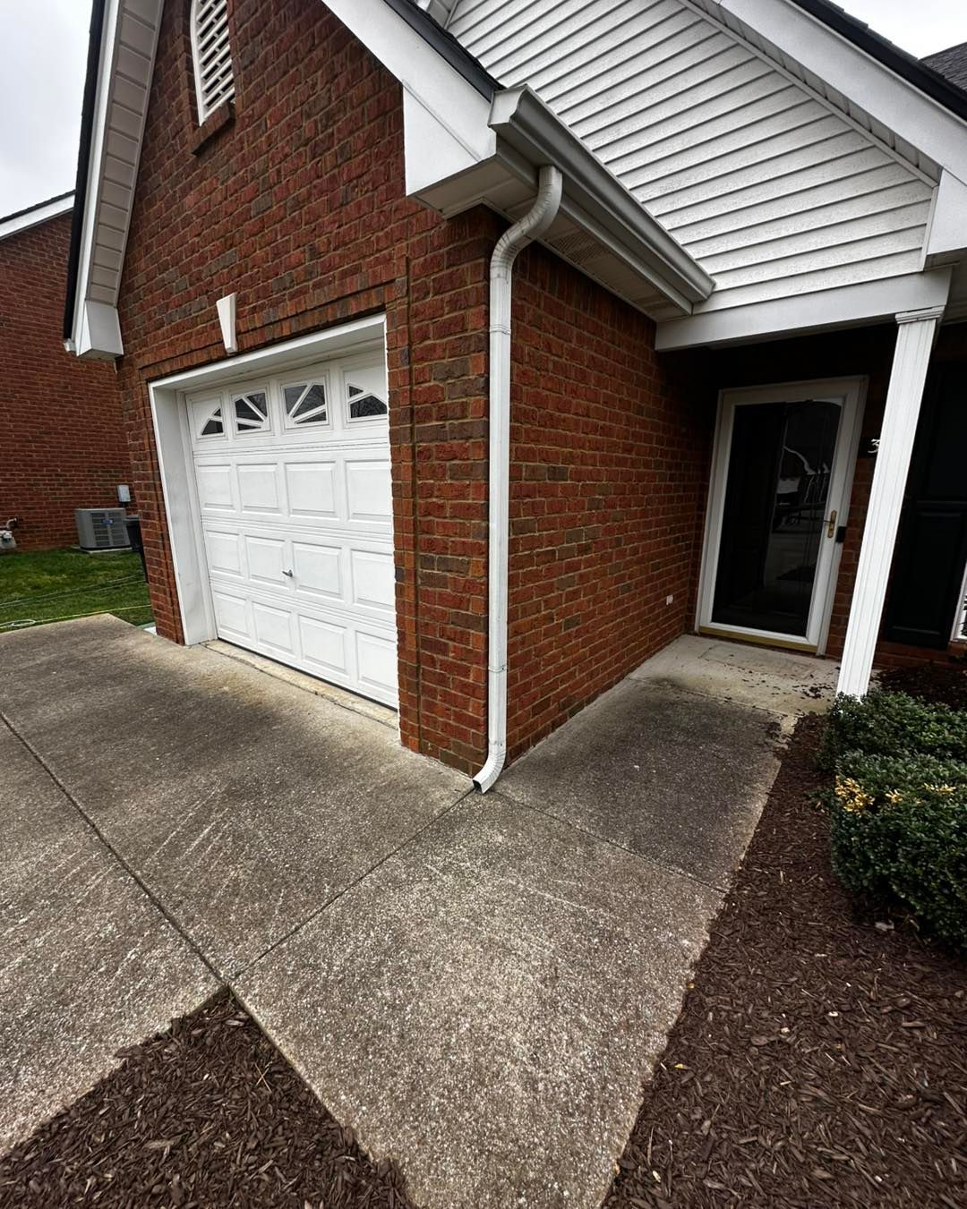 A brick house with a white garage door and a white door.