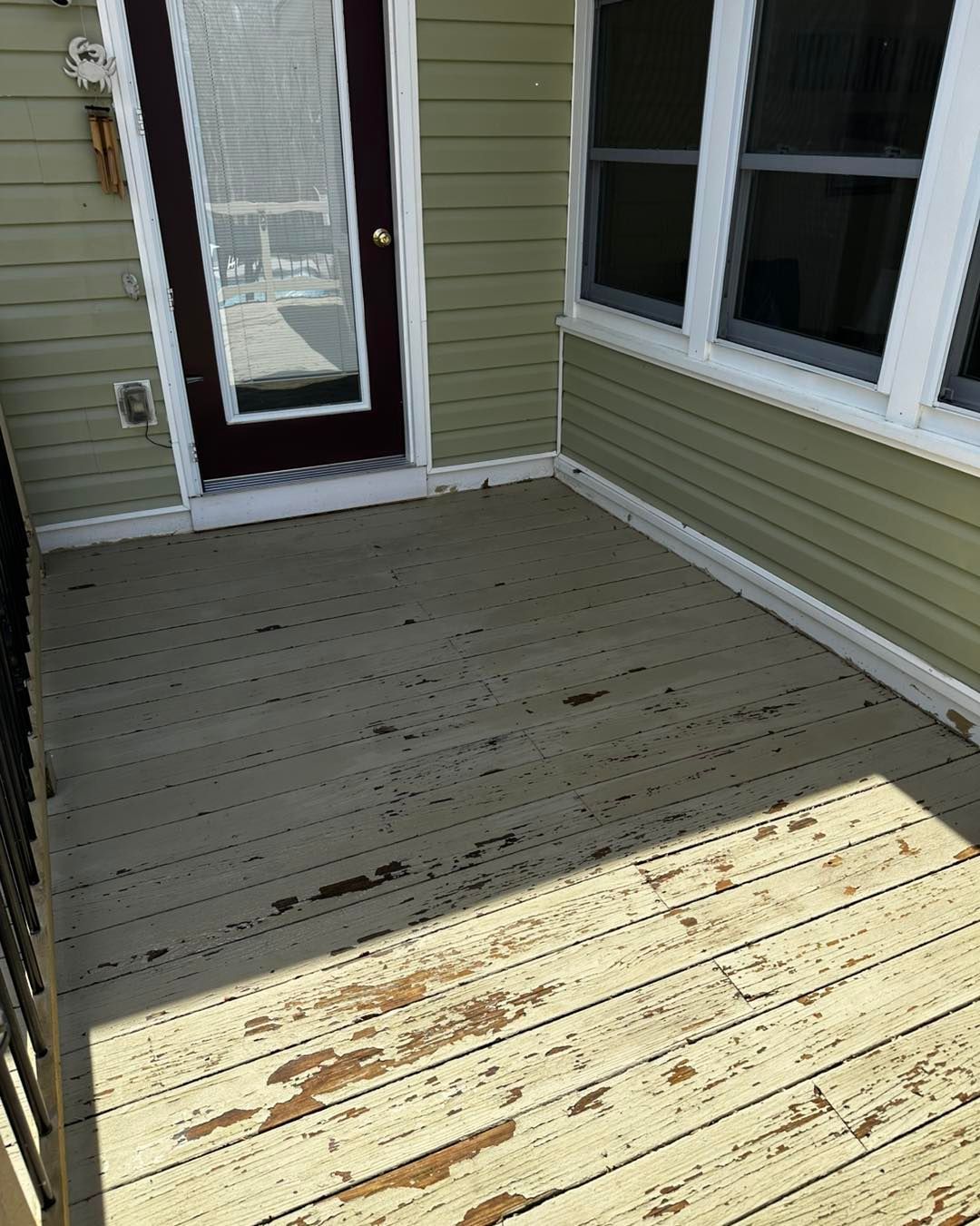 A wooden deck in front of a house with a door and windows.
