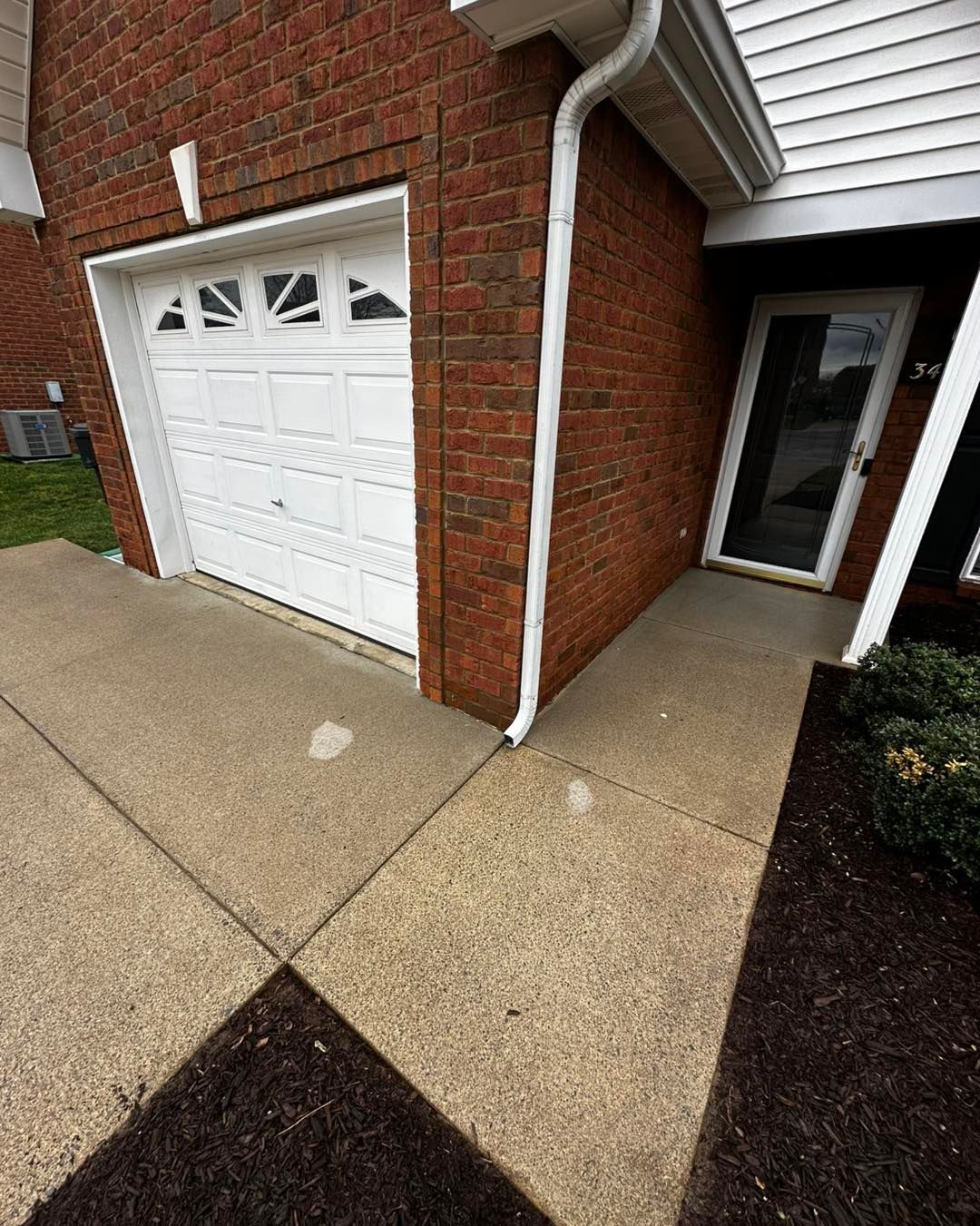 A brick house with a white garage door and a white door.