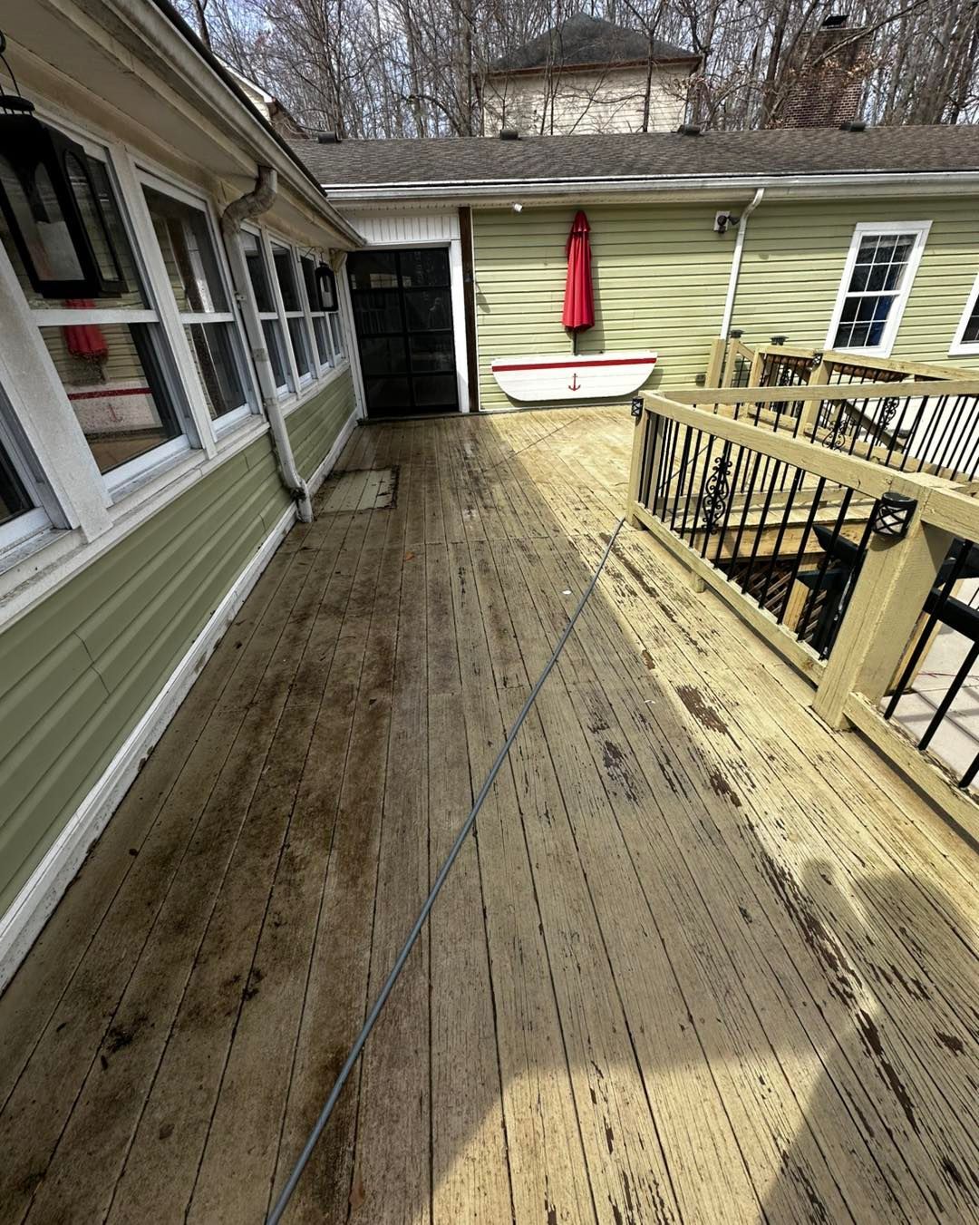 A wooden deck leading to a house with a red umbrella.