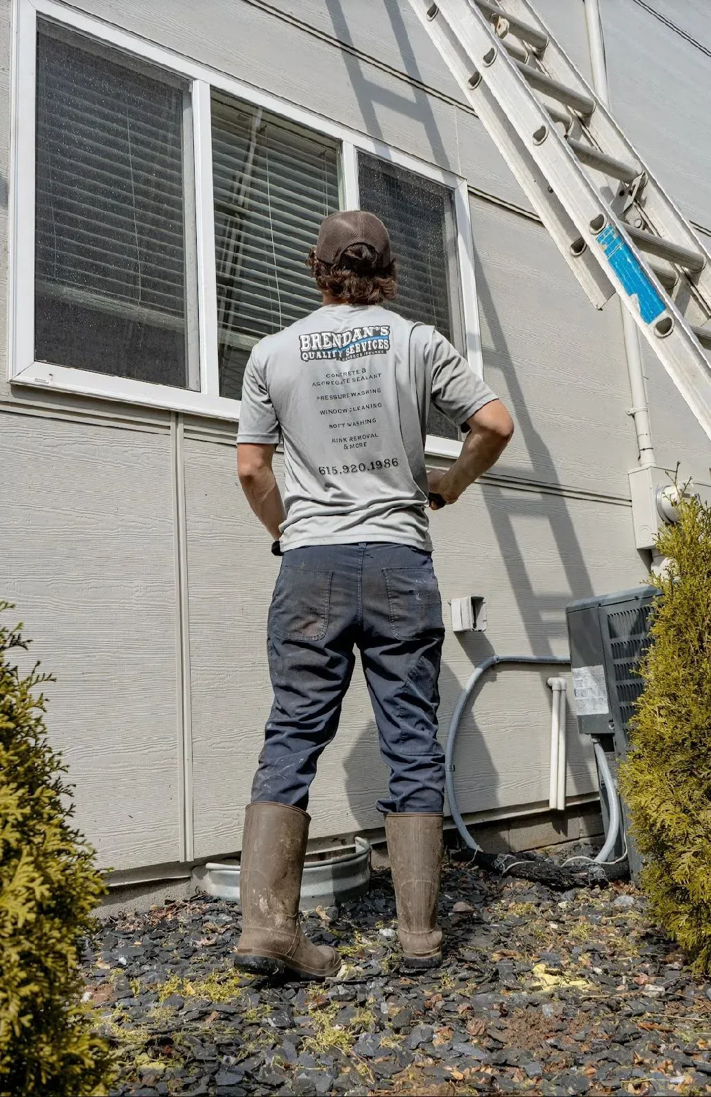 A man is standing in front of a building with a ladder in the background.