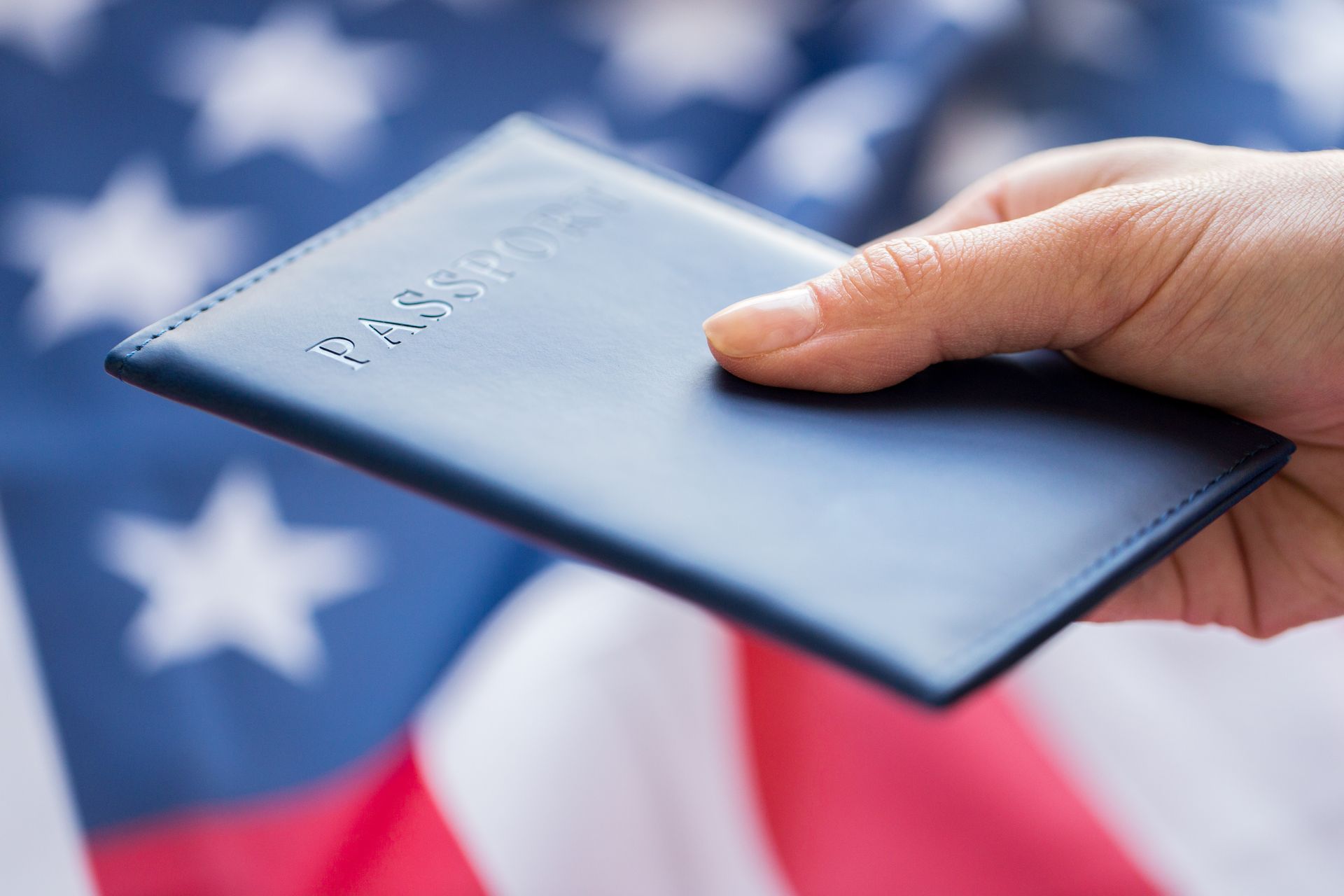 Hand holding a passport in front of the American flag representing citizenship in Kansas City.