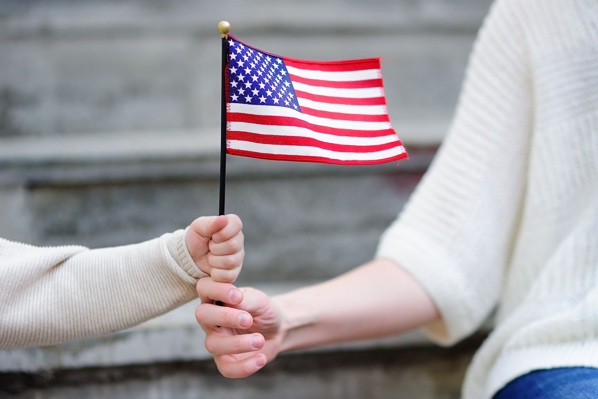 A woman and child are holding hands and holding an american flag.