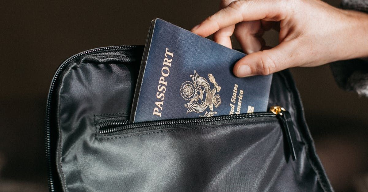 A person is putting a passport into a black bag.