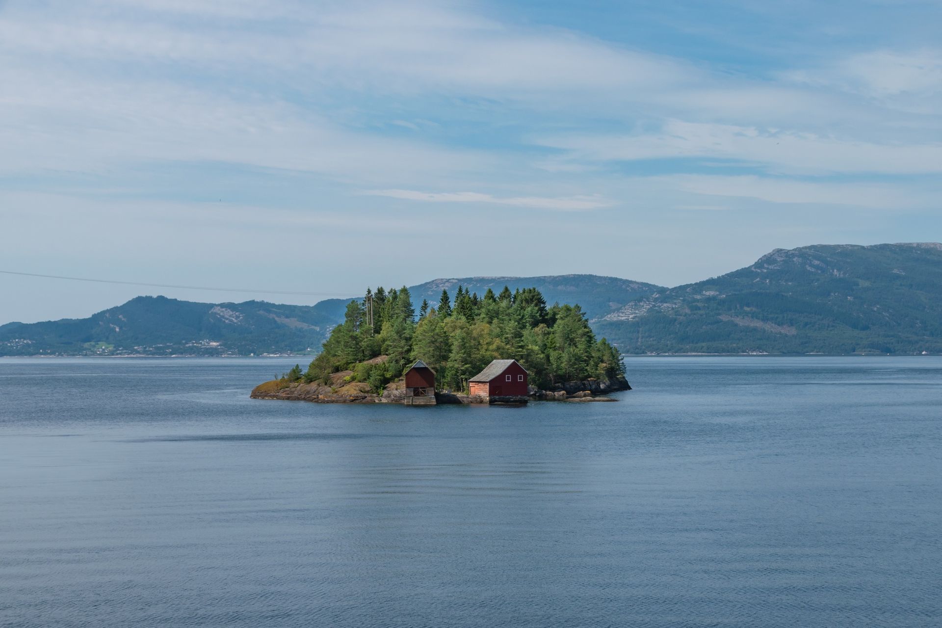 A small island in the middle of a lake with mountains in the background.