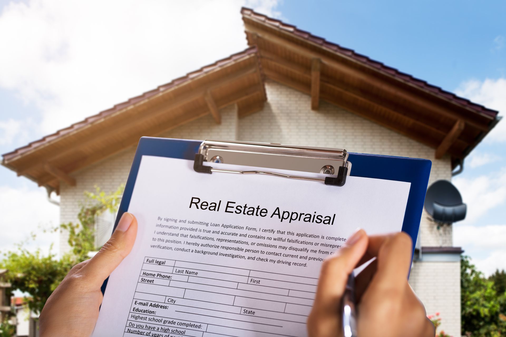 A person is holding a clipboard with a real estate appraisal on it in front of a house.